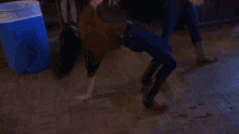 a woman is doing a handstand on a tiled floor in a dark room .