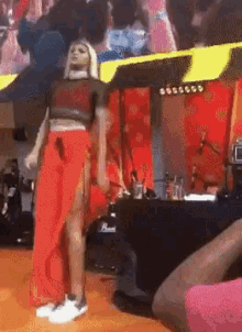 a woman in a crop top and red pants is standing on a stage .