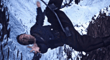 a man in a black jacket and black pants is laying on his back in the snow