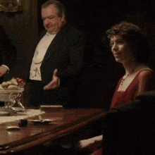 a man in a tuxedo and a woman in a red dress are sitting at a table