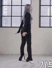 a woman in black pants and white boots is dancing in front of a window with a foreign language written on the bottom