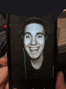 a person is holding a cell phone with a picture of a smiling man wearing headphones