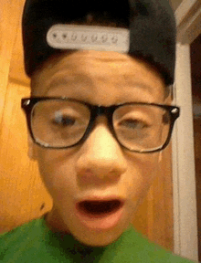 a young boy wearing glasses and a hat making a funny face