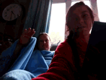 two women are sitting in front of a clock that shows the time as 8:17