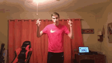 a man wearing a red nike shirt is standing in front of a laptop
