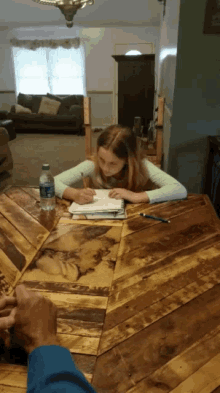 a girl sits at a table with a bottle of water