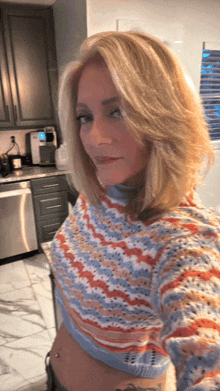 a woman in a colorful sweater is taking a selfie
