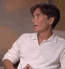 a man in a white polo shirt is sitting down