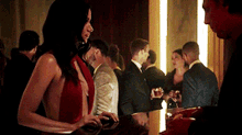 a woman in a red dress is standing in front of a crowd of people