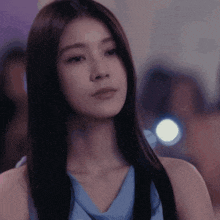 a woman in a blue dress looks at the camera
