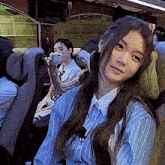 a woman is sitting in a bus taking a picture of herself with her phone .