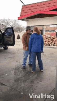 a man and a woman are standing in front of a building that says viralhog on it