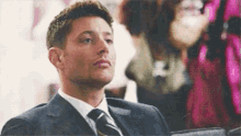 a man in a suit and tie is sitting down