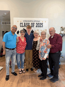 a group of people pose in front of a congratulations class of 2025 sign