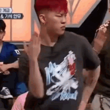 a young man with red hair is giving the middle finger while wearing a black shirt .