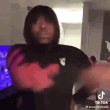 a man in a hoodie is dancing in front of a television .