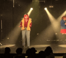 a man in a yellow vest is standing on a stage in front of a crowd