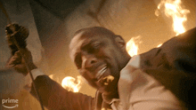 a man in a suit is holding a gun in front of a fire and the word prime is on the bottom