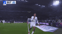 a soccer player celebrates a goal in front of a scoreboard that says 1 but