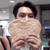 a man holding a heart shaped tortilla chip in front of his face