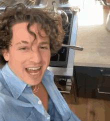a man with curly hair sitting in front of a stove