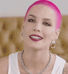 a woman with pink hair is wearing a white tank top and silver necklace