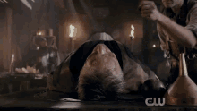 a man is laying on a table with a cw logo on the bottom right