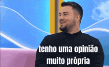 a man with a beard is sitting on a pink couch with the words " tenho uma opiniao muito propria " below him