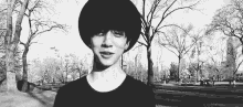 a black and white photo of a young man wearing a hat and a black shirt in a park .