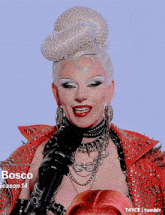 a drag queen is holding a microphone and smiling .