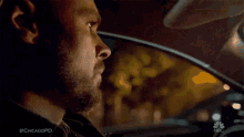 a man with a beard is sitting in a car at night .