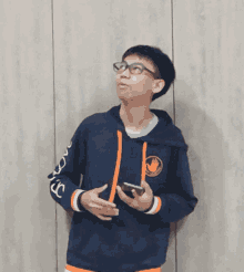 a boy wearing a blue sweatshirt with the letter r on the sleeve is holding a cell phone