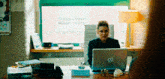 a woman sits at a desk with a hp laptop