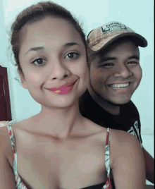 a man and a woman are posing for a picture and the man is wearing a hat that says ' g ' on it