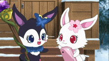 a black and white rabbit with a flower on its ear stands next to a white rabbit