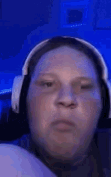 a man wearing headphones is making a funny face in front of a blue light .