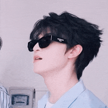a young man wearing sunglasses and a light blue shirt