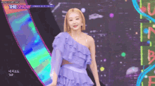 a woman in a purple one shoulder dress is dancing on a stage