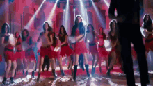a group of women in red dresses are dancing on a stage in a club .