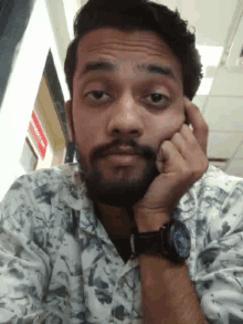 a man with a beard is wearing a watch and making a face