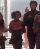 a blurry picture of a group of people walking in a room holding red boxes .