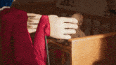 a woman in a red dress is standing in a room with a dresser and a crib