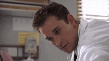 a close up of a man in a lab coat looking down .