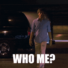 a man in a blue shirt is walking down the street with the words who me