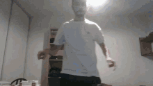 a man in a white shirt and black shorts is dancing in a room