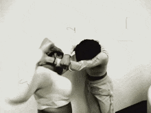 a black and white photo of two people fighting against a white wall