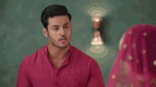 a man in a pink shirt is pointing at a woman in a pink veil