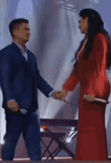 a man in a suit and a woman in a red dress holding hands