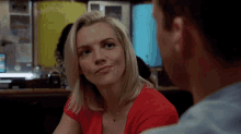 a woman in a red top is looking at a man in a blue shirt