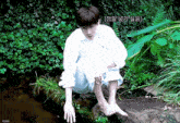 a man in a white shirt is sitting on a rock near a stream with a caption in korean